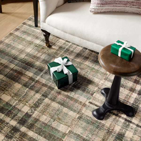 Plaid-striped rug in green and natural hues with a Christmas gift on top of it.